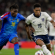 Jogadores da República Democrática do Congo e da Inglaterra disputam a bola durante partida da Copa do Mundo de 2026, representando o confronto pelas oitavas de final em Atlanta.